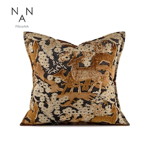 May include: Square cushion with a deer and floral design. The cushion features a brown and gold deer scene against a black and cream floral background. The brand name "PillowNA" is printed in the upper left corner.