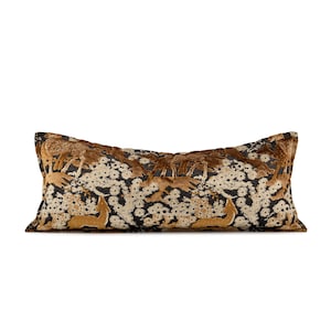 May include: A rectangular cushion with a forest scene design. The cushion has a black background with a pattern of white flowers and gold-coloured deer. The top and bottom edges are a dark brown.