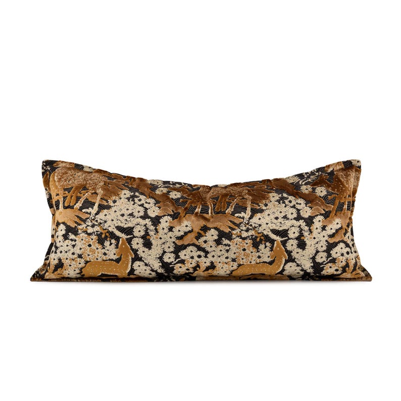 May include: A rectangular cushion with a forest scene design. The cushion has a black background with a pattern of white flowers and gold-coloured deer. The top and bottom edges are a dark brown.
