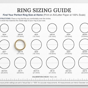 May include: A ring sizing guide printed on white paper with black text and circles. The guide includes US ring sizes from 4 to 13, with corresponding millimeter measurements. A gold ring is placed on the US 7.5 circle. The guide also includes a calibration check.