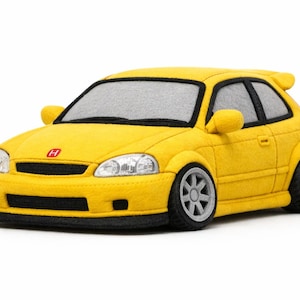 May include: A yellow toy car with a spoiler, black accents, and gray wheels. The car has a red emblem on the front and a black front lip. The windows are gray. This toy car is a replica of a Honda Civic.