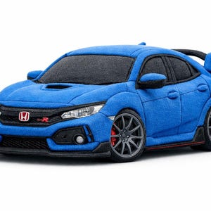 Può includere: Un'auto giocattolo in peluche blu, una Honda Civic Type R, con dettagli neri. L'auto giocattolo ha uno spoiler, ruote e il logo Honda. L'auto è progettata per assomigliare al veicolo reale.