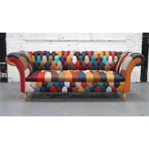 May include: A multi-coloured patchwork sofa with a buttoned back and seat. The sofa is upholstered in various leather patches in shades of red, blue, orange, and green. The arms are curved, and the sofa has wooden legs.
