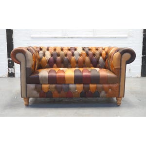 May include: A two-seater sofa with a patchwork design. The sofa has a button-tufted back and seat, with leather patches in brown, tan, and burgundy. The arms and base are a lighter tan, and the legs are made of wood. The sofa is approximately 150 cm in length.