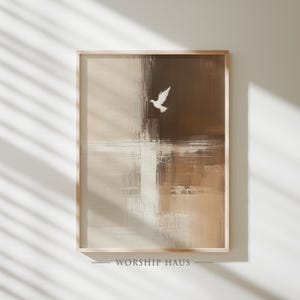 May include: Framed abstract art print featuring a white dove in flight against a backdrop of beige, brown, and white brushstrokes. The artwork is in a wooden frame, with the text "WORSHIP HAUS" at the bottom.