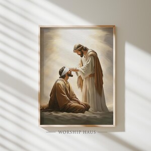 Könnte beinhalten: Gerahmter Kunstdruck, der eine religiöse Szene darstellt. Zwei Figuren sind zu sehen, eine kniend mit Augenbinde, die andere berührt sein Gesicht. Die Figuren tragen Gewänder, mit einer warmen Farbpalette. Der Text "WORSHIP HAUS" befindet sich unten.