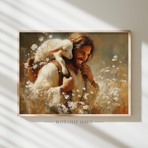 Op de afbeelding: Een ingelijste prent toont een lachende figuur die een lam draagt, omringd door witte bloemen. Het kunstwerk heeft een warm kleurenpalet met zachte belichting. De tekst "WORSHIP HAUS" staat onderaan het frame.