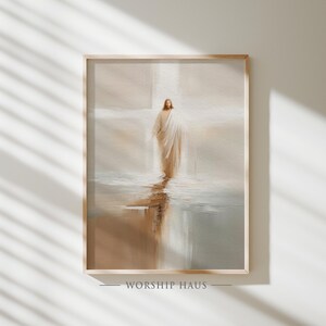May include: Framed art print featuring a serene depiction of a figure in flowing white robes, standing in water with a soft, ethereal glow. The artwork has a muted color palette of beige, brown, and white. The text "WORSHIP HAUS" is at the bottom.
