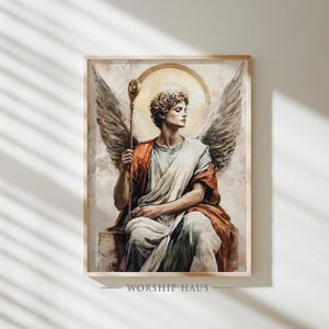 May include: A framed print of an angel with large wings, a golden halo, and a staff. The angel is draped in white and orange robes, seated with a contemplative expression. The artwork has a vintage, painterly style.