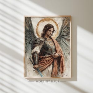 May include: Watercolor painting of an angel with large feathered wings, wearing armor and holding a sword. The angel has a golden halo and is draped in a red cloth. The artwork is framed and has the text "WORSHIP HAUS" at the bottom.