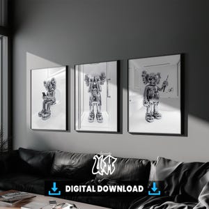 May include: Three framed wall art prints featuring a metallic silver character with X-shaped eyes in various poses. The first shows the figure sitting on a toilet, the second standing with hands over its face, and the third holding a toothbrush.