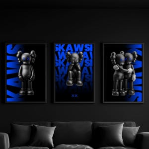 May include: Three framed art prints showcasing black figures with blue detailing and the word "KAWS" in blue. The figures are in various poses: standing, covering eyes, and embracing. The prints are displayed above a black sofa.