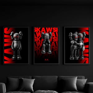 May include: Three framed art prints showcasing black figures with red X eyes and the word "KAWS" in red. The figures are in various poses against a black and red gradient backdrop. The prints are displayed above a black sofa.