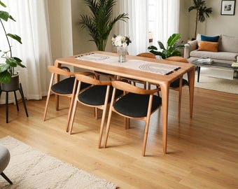May include: A light wood dining table with six matching chairs. The chairs have black seats and curved wooden backs. A decorative runner sits on the table, and the room has hardwood floors and large windows.