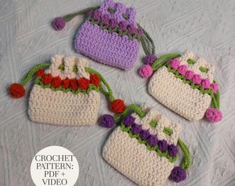 May include: Three small crochet drawstring pouches. One is light purple with a green trim and purple bobbles. Two are cream-colored with green trim and either red or purple bobbles. A white circular label reads CROCHET PATTERN: PDF + VIDEO.