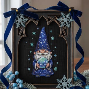 May include: A framed cross-stitch featuring a blue wizard gnome holding a globe, set against a black background. The frame is dark brown with an arched design, adorned with blue velvet ribbon, snowflake accents, and faux berries. The overall theme is winter or fantasy.