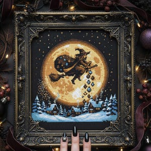 May include: Cross-stitch art in a dark ornate frame depicts a witch on a broom flying in front of a full moon. The scene includes a snowy village and falling gems. The color palette is dark with gold, brown, and blue accents.