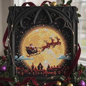 Puede incluir: Un bordado enmarcado que representa a Papá Noel en su trineo, tirado por renos, frente a una luna llena. La escena incluye una silueta de pueblo. El marco negro tiene un diseño de arco gótico. Decoraciones festivas con acebo, cinta y luces.