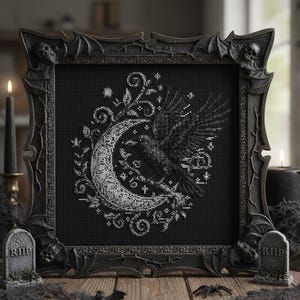 Puede incluir: Arte de punto de cruz enmarcado en negro con un cuervo posado en una luna creciente. La obra de arte es en blanco y negro, con un marco de estilo gótico. La escena incluye velas, lápidas y decoraciones de telarañas, creando un tema de Halloween.