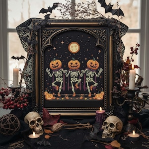May include: A framed Halloween cross-stitch featuring three skeletons with pumpkin heads dancing under a full moon. The artwork is set against a starry black background, framed in ornate gold, and decorated with bats and candles.