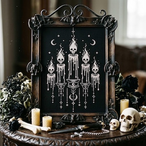 Puede incluir: Un bordado en punto de cruz negro enmarcado con velas blancas con llamas de calaveras. El marco es marrón oscuro con detalles de murciélagos y gárgolas. Incluye velas, calaveras, huesos y un cuchillo decorativo, creando un tema gótico o de Halloween.