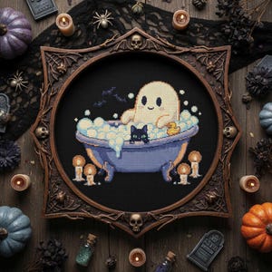 Puede incluir: Un punto de cruz enmarcado con un fantasma de dibujos animados en una bañera azul con burbujas, un gato negro y un patito de goma. El marco marrón oscuro tiene elementos decorativos. El fondo es negro y el tema es Halloween.
