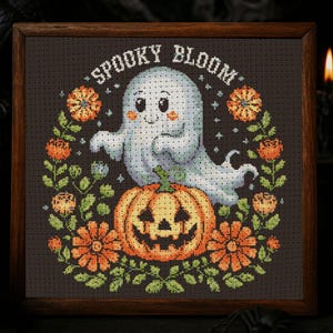 May include: Cross-stitch artwork in a wooden frame featuring a friendly ghost above a carved pumpkin. The design includes orange flowers and the text "Spooky Bloom" on a dark background. A Halloween-themed decorative piece.