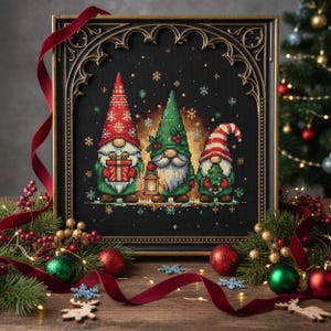 May include: A framed cross-stitch featuring three Christmas gnomes. The gnomes wear red and green hats and hold a gift, lantern, and Christmas tree. The frame is ornate with a dark finish, and the background is black. The image is decorated with Christmas ornaments and a red ribbon.