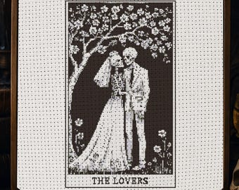 Könnte beinhalten: Kreuzstich-Kunstwerk in einem Holzrahmen mit einem Schwarz-Weiß-Bild von zwei Skeletten unter einem blühenden Baum. Die Skelette tragen Hochzeitskleidung. Der Text "THE LOVERS" befindet sich unten.