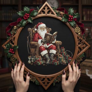 以下が含まれることがあります： 本を読むサンタクロースのクロスステッチ。プレゼントに囲まれています。作品は、ヒイラギと赤いリボンのアクセントが付いた、星型の木製フレームに額装されています。サンタは赤いスーツと帽子を着用し、詳細なアームチェアに座っています。