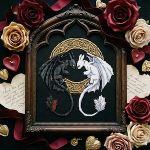 Puede incluir: Arte de punto de cruz de dos dragones, uno negro y otro blanco, enfrentados dentro de un círculo de nudos celtas dorados, enmarcado en un marco de madera oscura. Rodeado de rosas rojas y doradas, velas y decoraciones en forma de corazón.