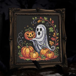 May include: Cross-stitch artwork in a dark ornate frame. The image features a friendly ghost holding a carved pumpkin, surrounded by pumpkins and autumn foliage. The background is black.