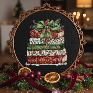 May include: A cross-stitch design of a stack of books, each with a unique pattern in red, green, and white, topped with a green bow. The artwork is framed in a decorative wooden hoop, with Christmas decorations around the base.