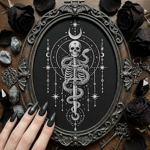 May include: Oval framed gothic cross-stitch art featuring a skeleton with a snake wrapped around a sword. The black and white design includes a crescent moon, stars, and celestial elements. The frame is dark brown with decorative details, and the background includes black roses and keys.