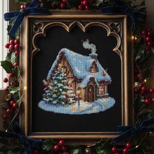 Puede incluir: Punto de cruz de una cabaña cubierta de nieve con un árbol de Navidad, enmarcada en un marco de madera decorativo. La cabaña tiene una ventana iluminada y una chimenea humeante. El marco está rodeado de acebo, bayas rojas y lazos de terciopelo azul.