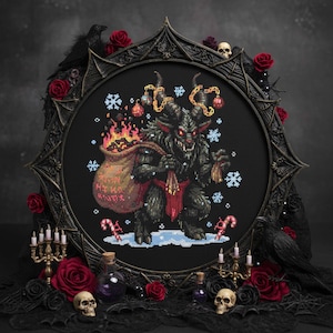 May include: A framed cross-stitch featuring a Krampus figure with a sack of burning coals, surrounded by snowflakes and candy canes. The black frame is adorned with red roses, skulls, and a raven. The overall theme is gothic and holiday-themed.