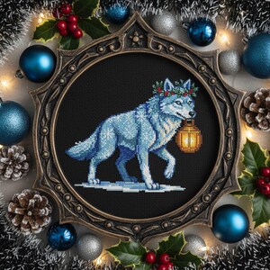 May include: A cross-stitch artwork of a blue wolf wearing a wreath and carrying a lantern, set in a decorative frame. The frame is surrounded by Christmas ornaments, pinecones, and holly. The color palette includes blue, gold, and brown.