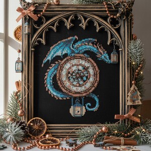 May include: Cross-stitch art of a blue dragon wrapped around a clock face, set against a black background. The artwork is framed in a dark, ornate wooden frame. Decorative elements include pine, ornaments, and dried orange slices.