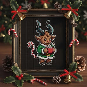 May include: A framed cross-stitch of a festive creature holding a mug of cocoa. The creature has horns and is wearing a green outfit with a white trim. The frame is surrounded by Christmas decorations, including candy canes, bells, and holly.