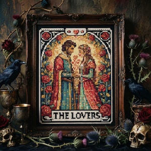 Può includere: Opera d'arte a punto croce incorniciata, raffigurante una coppia in abiti medievali, circondata da rose e con la scritta "THE LOVERS". L'immagine è in una cornice di legno scuro con elementi decorativi come corvi, teschi e cardi.