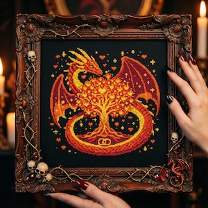 Può includere: Opera d'arte a punto croce raffigurante un drago e un albero nei toni dell'arancione e del giallo su sfondo nero. L'opera è incorniciata in una cornice marrone scuro e ornata, con teschi decorativi e un motivo a drago.