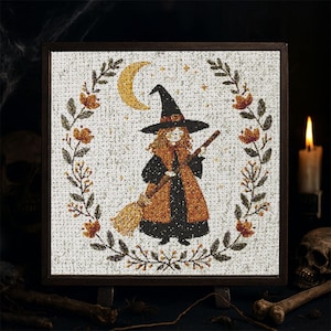Könnte beinhalten: Kreuzstich-Kunst einer Hexe mit schwarzem Hut und orangefarbenem Mantel, die einen Besen hält. Die Hexe ist von einem floralen Kranz mit Mond und Sternen umgeben. Das Kunstwerk ist in einem dunkelbraunen Holzrahmen gerahmt.