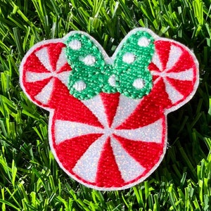 May include: Red and white peppermint candy cane design with a green bow with white polka dots. This is a felt applique patch.