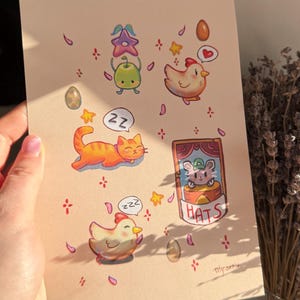 May include: A whimsical illustration featuring cartoon animals and objects. The artwork includes a sleeping orange cat, a chicken, and a mouse in a box labeled "HATS." Decorative elements like eggs, stars, and flowers are scattered around the characters.