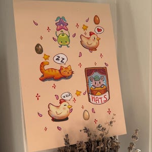 May include: A whimsical illustration featuring cartoon animals and objects. The artwork includes a sleeping orange cat, a chicken, a green creature, and a mouse in a hat. The word "HATS" is also visible. The background is a light peach color.