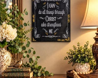 May include: A rectangular black wall sign featuring white decorative script text that reads, I CAN do all things through CHRIST who strengthens ME, framed by white scrollwork and gold-colored corner accents on a dark background.