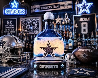 May include: A decorative bottle with a star design and the word "COWBOYS" on the base. The image includes a football, a helmet, and a jersey with the number 8. The background features neon signs and other team-related items.