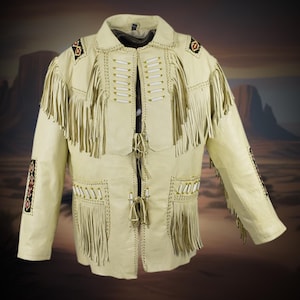 May include: Cream-colored leather jacket with fringe detailing on the chest, sleeves, and pockets. The jacket features decorative beadwork on the shoulders and sleeves, and a collared neckline. The jacket has a button-up front and a Western-inspired design.