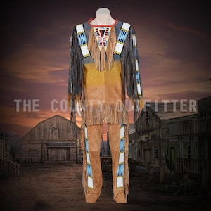 Puede incluir: Un atuendo nativo americano marrón y beige con flecos y abalorios. El atuendo incluye una camisa de manga larga y pantalones. La camisa tiene un cuello rojo y un diseño geométrico en el pecho. El texto "THE COUNTY OUTFITTER" es visible.