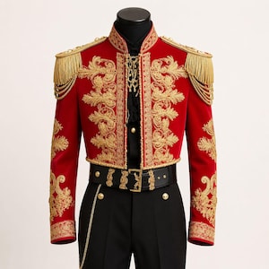 May include: A red cropped jacket with gold embroidery and fringe epaulettes. The jacket features ornate gold floral patterns and is paired with black pants and a black belt with gold accents. A black shirt is visible underneath.